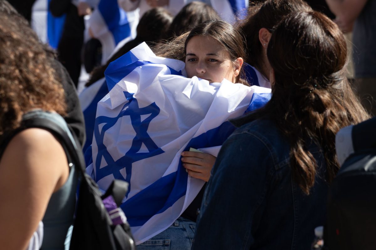 Students draped with the Israeli Flag hug as they are filled with emotion at the Oct. 7 Memorial held on the Main Quad this Monday.