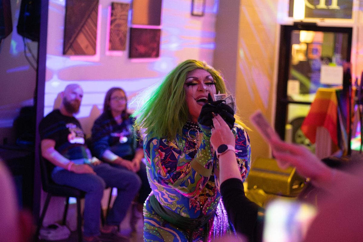 Apollo Summers captivates the audience with a striking drag performance dressed in an eye-catching outfit and collects tips from audience members at the Gallery Art Bar in Downtown Urbana on Friday, Oct. 25.