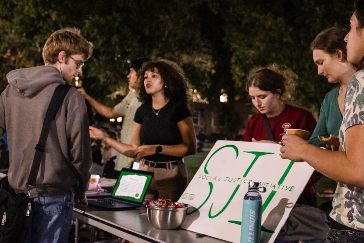 The Social Justice Initiative speaks to students at the block party hosted by Illini Vote at Anniversary Plaza on Tuesday. Both students and community members can vote early in-person at the Illini Union.