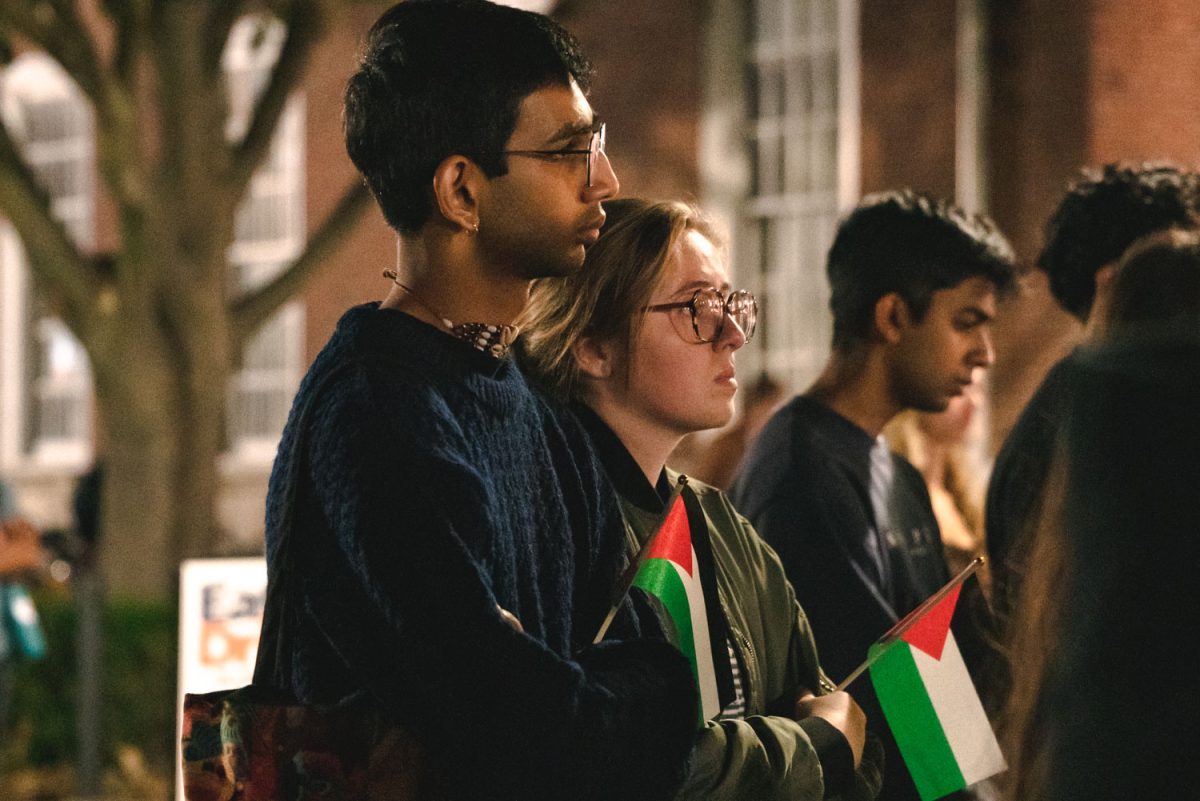 Attendees stand at Anniversary Plaza outside the Illini Union as SJP speakers inform those listening in regard to the loss of life in Palestine during their memorial event on Tuesday night.