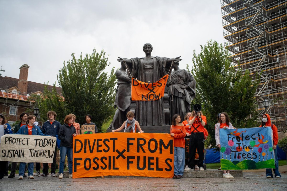 Protesters gathering on Friday to protest UI's involvement with fossil fuel companies. Organizers afix a banner reading "Divest Now" on Alma Mater on Sept. 27.