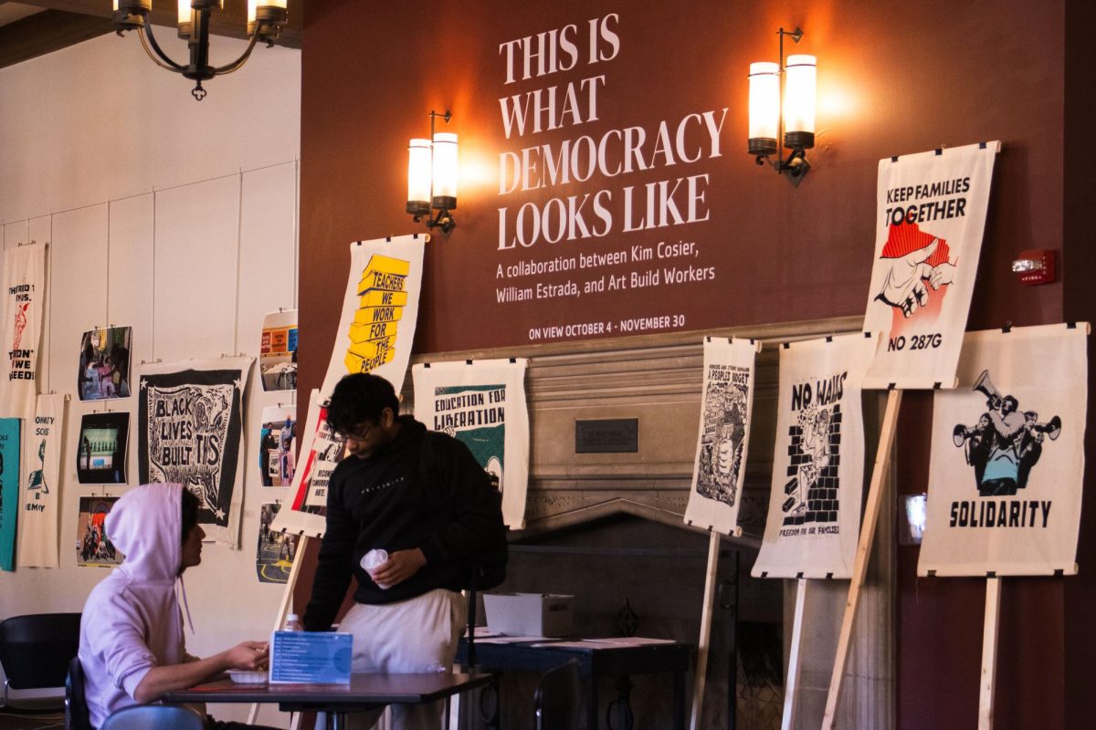 Community members work and view the “This is What Democracy Looks Like” art installation in the University YMCA on Friday. The installation features painted banners, picket signs, posters and opportunities for community members to make their own artwork encouraging voter participation. 