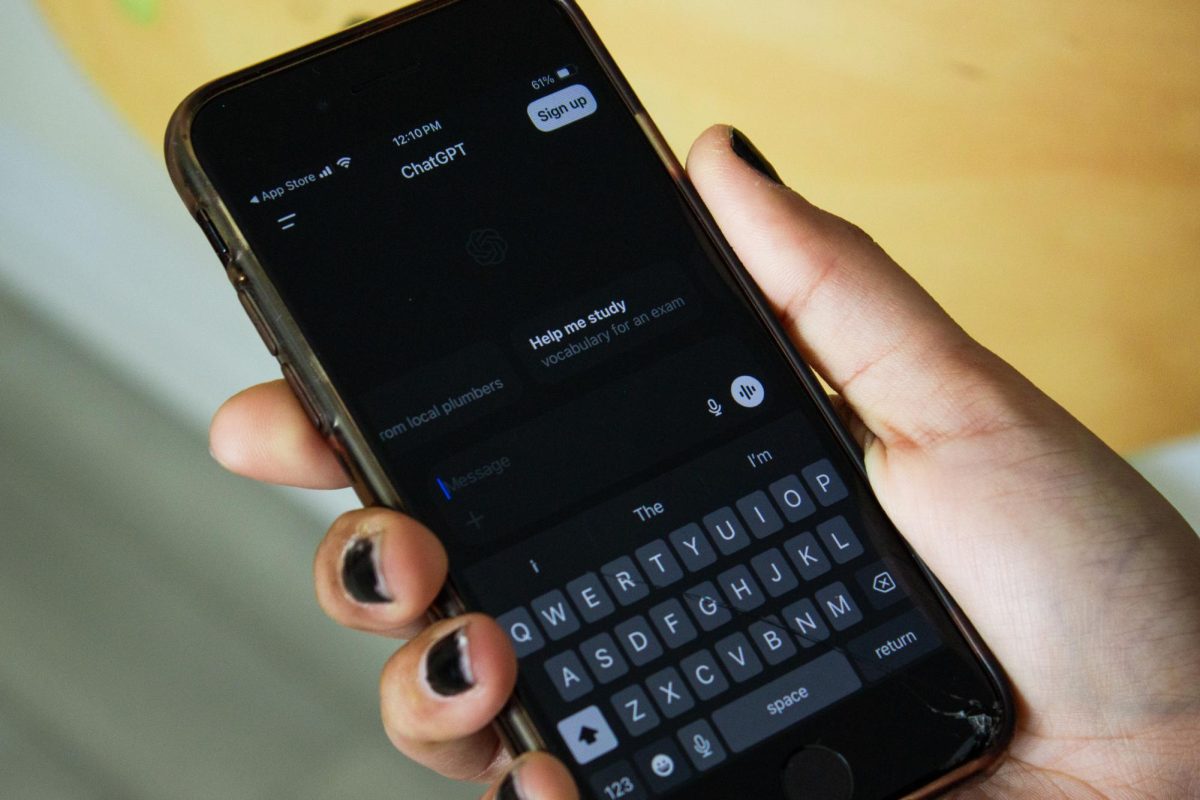 A student holds their phone with ChatGPT open.
