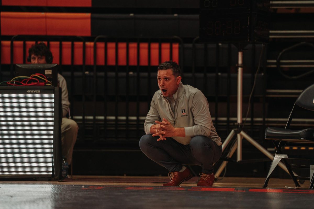 Illinois wrestling head coach Mike Poeta yells strategy at his wrestlers from beside the mat on Nov. 19, 2023.