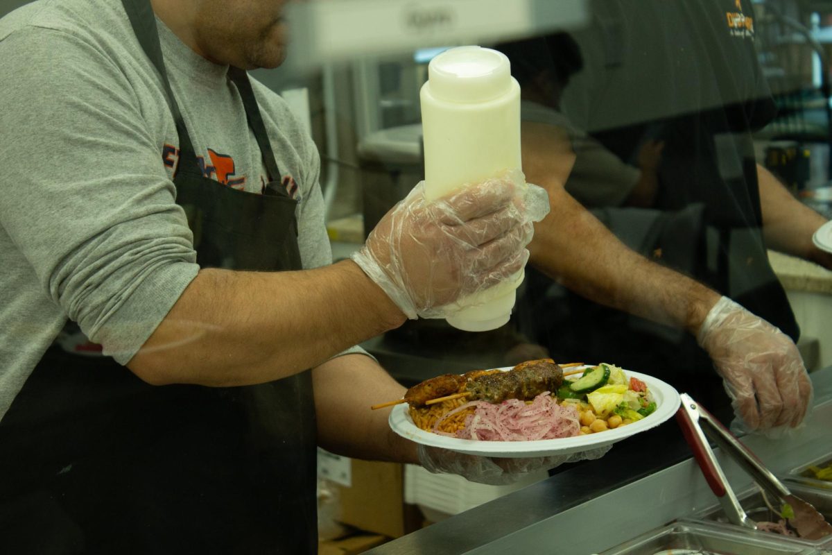 A Dubai Grill worker prepares a Kufta Kabab Bowl topped with creamy garlic sauce on Nov. 9.