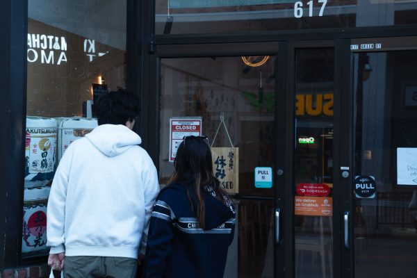 Two passerby take a look at a failed health inspection notice posted on the door of Japanese restaurant, Kaijken and Kyo Matcha located on 617 E. Green St. on Saturday afternoon.