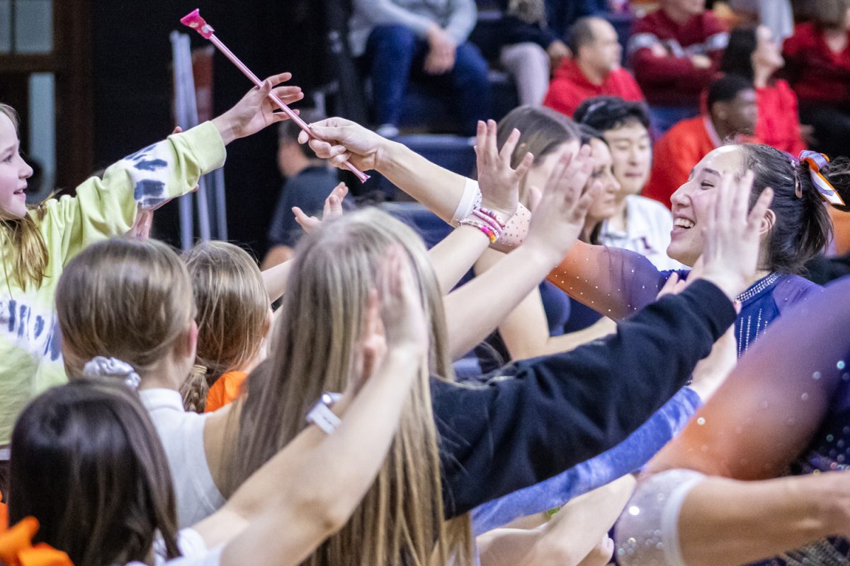 Freshman Chloe Cho hands candy to a young fan after her beam routine during a meet against Ohio State on Feb. 7. Illinois upset Ohio with a team score of 196.150-195.475.