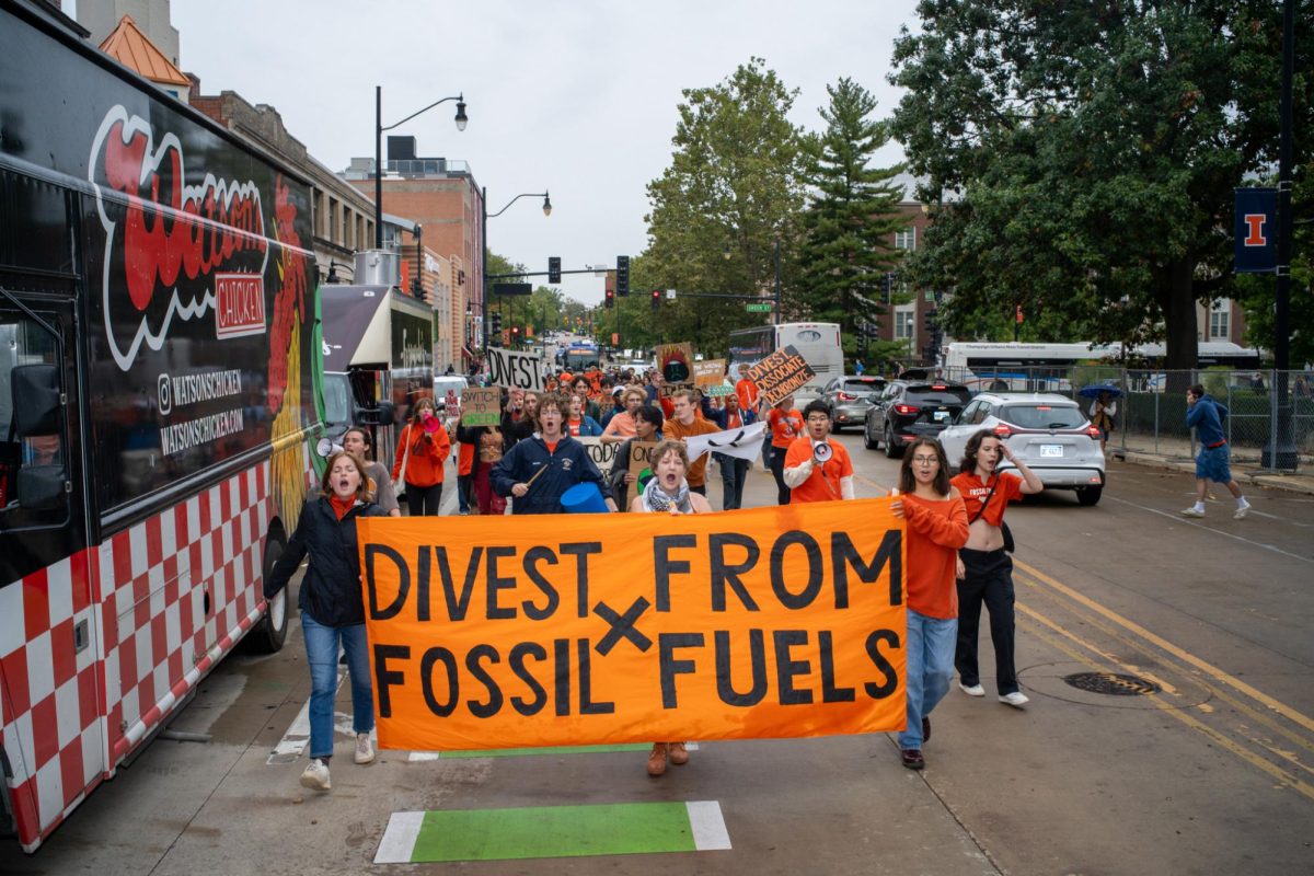 Protesters marching down Wright St on Friday to protest UI's involvement with fossil fuel companies. Attendees chant calling for divestment and underlining climate change's impact on the world.