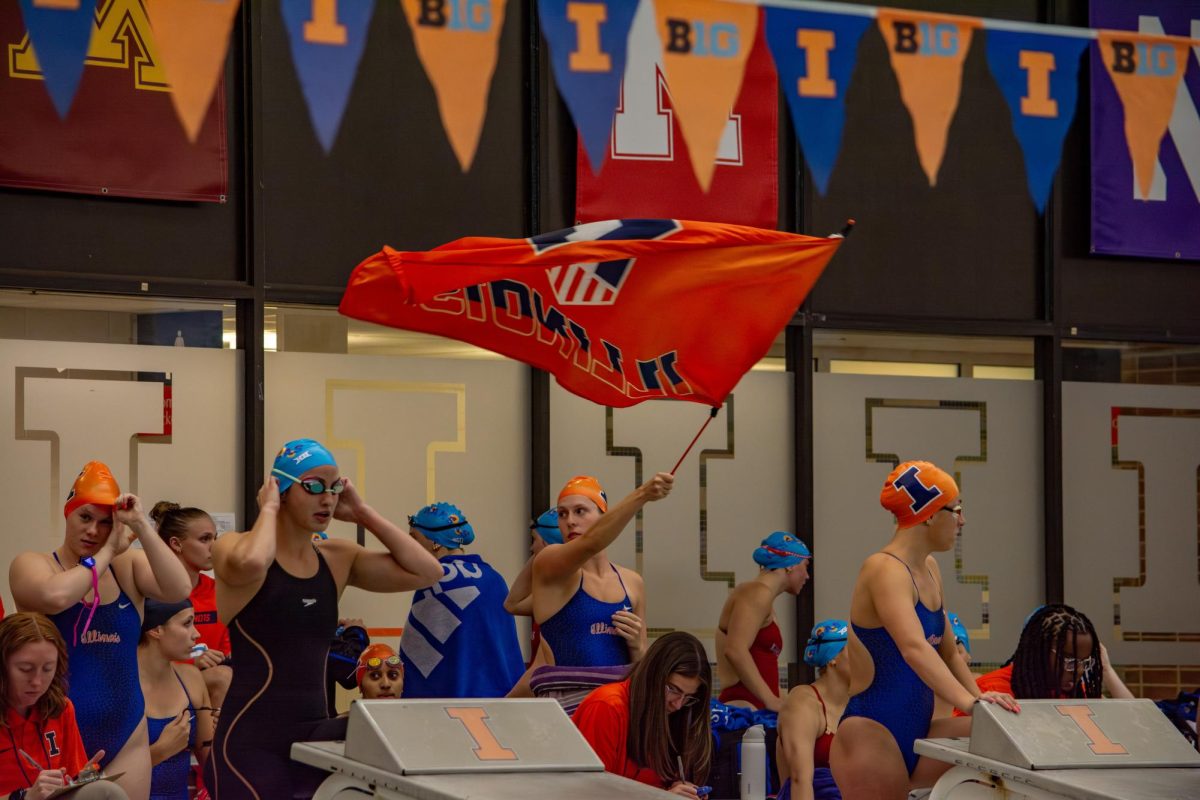 Senior freestyle swimmer Logan Kuehne waves an Illinois flag before swimmers step up on the diving blocks in the meet against Kansas on Oct. 10, 2024.