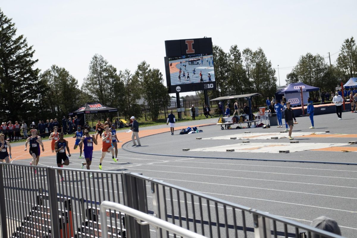 Runners race around the track corner during a relay on April 8, 2023.