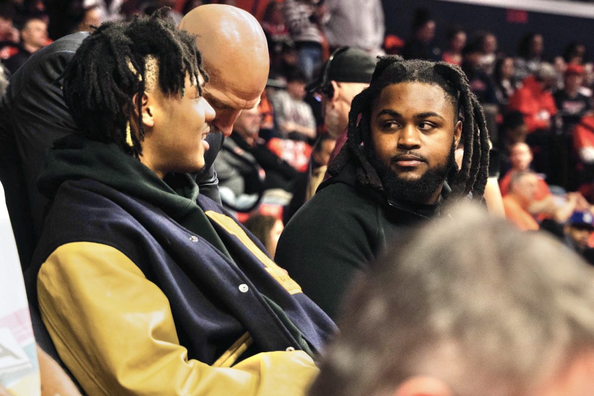 Former Illini football star Johnny Newton (right) sits with Terrence Shannon Jr. (left) at Illinois' home game against Michigan State on Feb. 15.