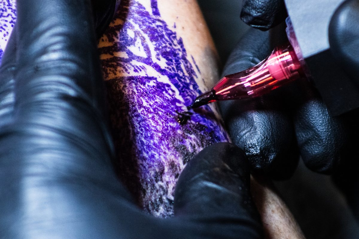 Matt Stines, owner of No Regrets Tattoos and Body Piercings, tattoos a realistic portrait of Jesus on a client's forearm Feb. 21. No Regrets is home to several local artists and piercers with unique styles and various levels of experience.