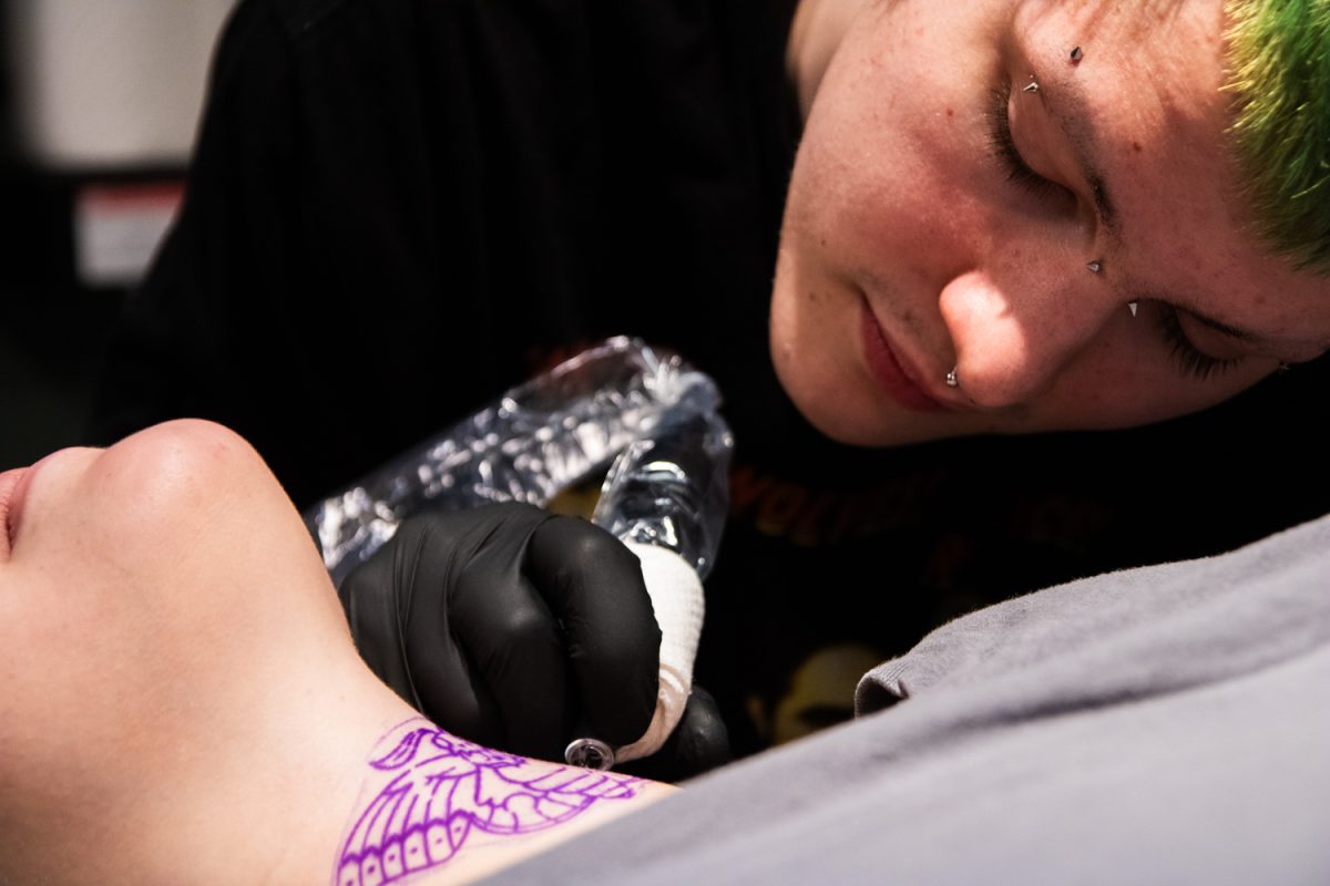 Artist Luc Caparoon tattoos a client's neck Feb. 21 at No Regrets Tattoos and Body Piercing in downtown Champaign. No Regrets is home to several local artists and piercers with unique styles and various levels of experience.
