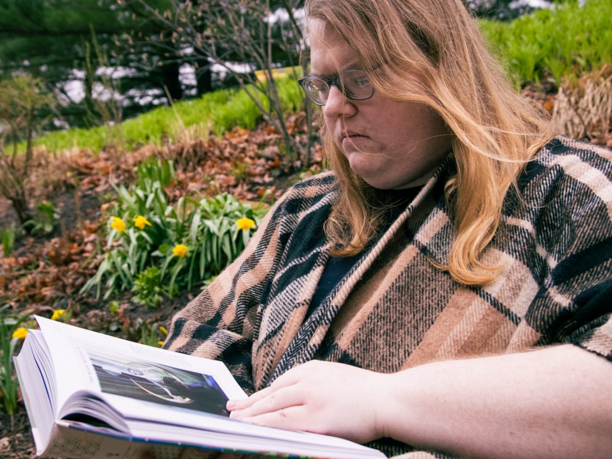 Mattie Fash, a graduate student studying poetry, holds books on witchcraft at Crystal Lake Park in Urbana on March 5. Fash lives near the park and visits it often to reconnect with nature.