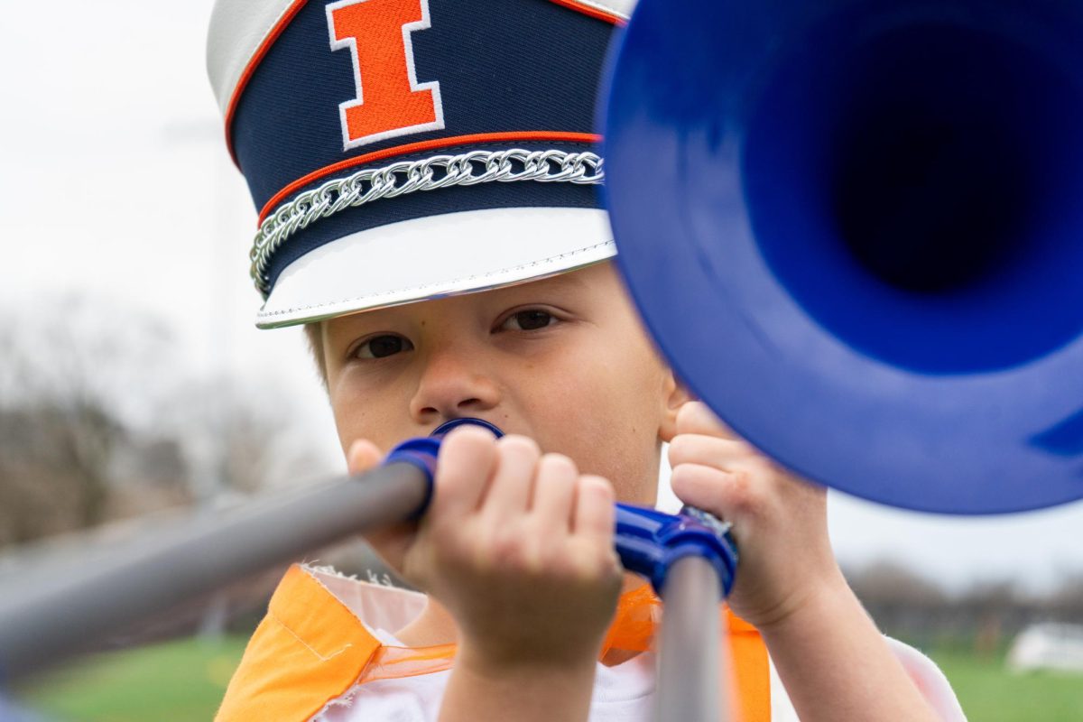 Milo, a second grader obsessed with the Marching Illini, stands tall in the Marching Illini Practice Field with his pBone on March 27. Milo frequents the field on the corner of E. Gregory Dr. and S. 1st St. to watch the marching illini practice.