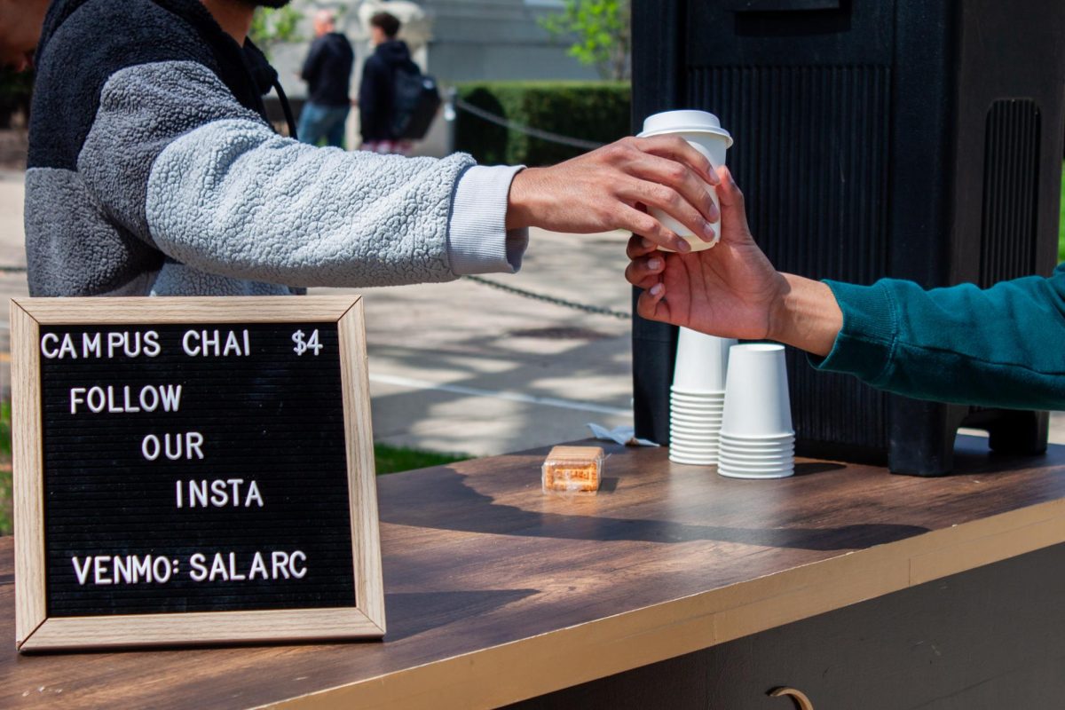 Isa Patel, one of the students that runs the cart, hands a customer a warm cup of chai outside the English building on the Main Quad on Monday.