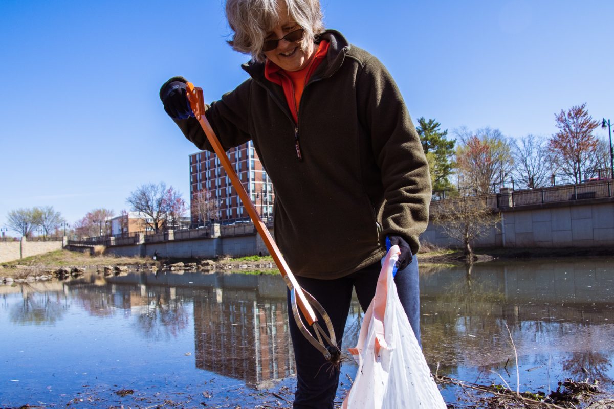 Kristin Hoganson, professor in LAS, removes trash from the Boneyard Creek at the Second Street Basin in Champaign on April 12.