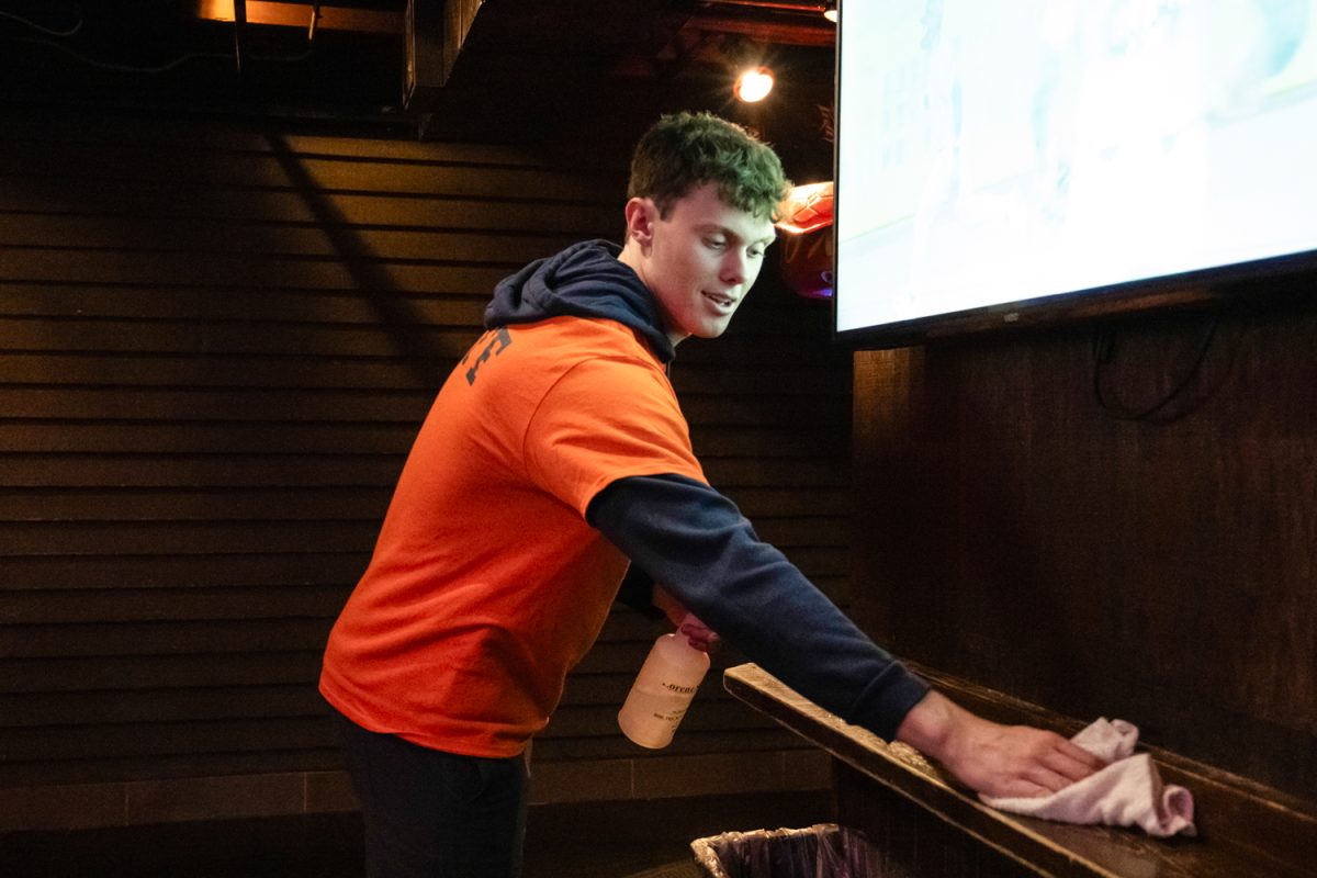 A head “door guy” at Joe's Brewery wipes down a counter at the popular going-out spot.