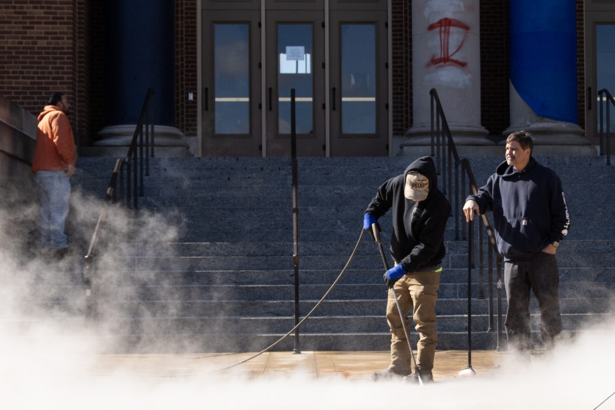 University Facilities & Services workers use high-pressure hoses to clean paint off of the ground in front of Foellinger Auditorium at 10 a.m. on April 8.