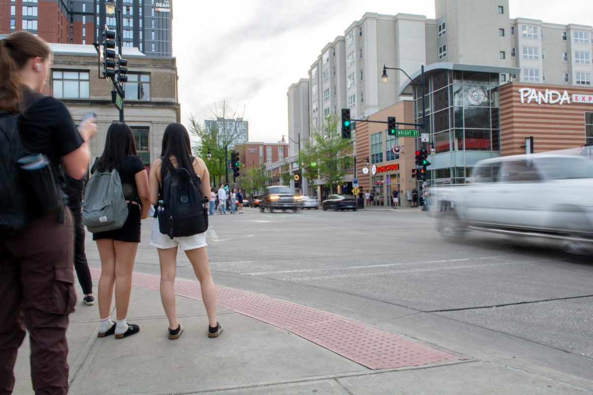Pedestrians wait to cross the intersection of Green and Wright Streets on April 23.Green Street has served as the heart of campustown for generations of students.