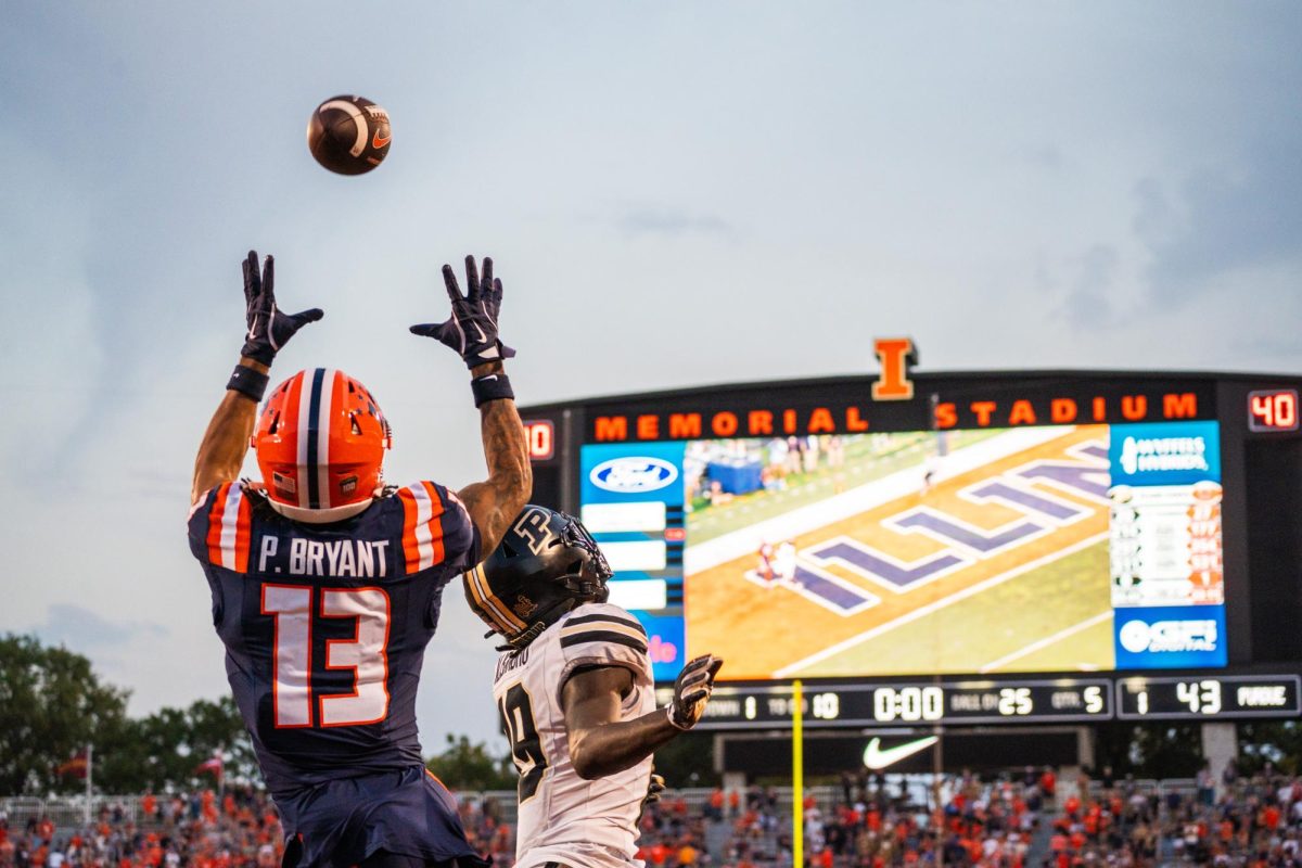 Wide receiver Pat Bryant leaps into the air and reaches for the sky as a pass comes hurling towards him over the opposing Purdue player's head in the Illinois v Purdue football game on Oct. 12, 2024 in Memorial Stadium.