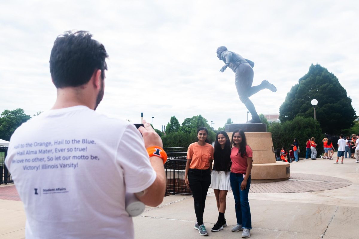 Students pose in front of Memorial Stadium while an Orientation team member takes their photo.