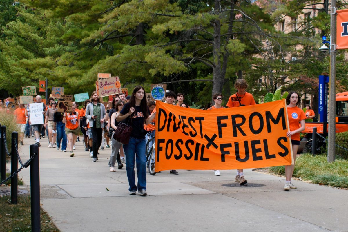 Traveling from Alma Mater toward Anniversary Plaza, Fossil Free Illinois protesters carry their signs and shout chants such as “The people united will never be defeated.” Fossil Free Illinois and other student groups held a rally Friday afternoon, calling on the University to divest from fossil fuels. 