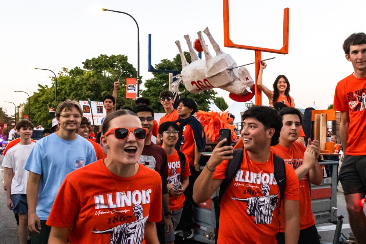 A float holding a portrayal of a dead USC Trojan horse roasting on a spit between two goal posts rolls down First Street with an entourage of students. (Adam Edwards)