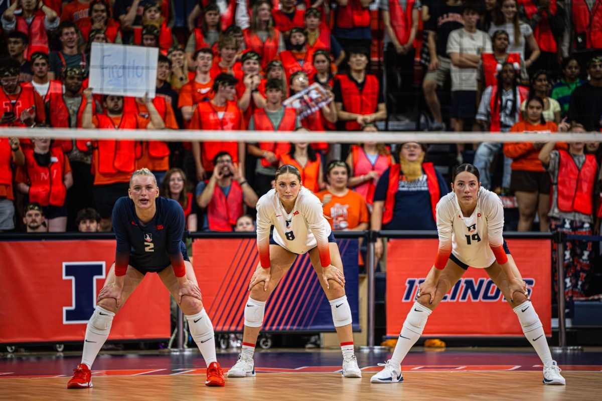 Freshman outside hitter Alyssa Aguayo (right), senior outside hitter/opposite Averie Hernandez (middle) and freshman libero/defensive specialist Taryn Kirsch (left) await the Oregon serve as they stand in front of a rowdy Illinois student section. Illinois won its Sept. 26 match against Oregon 3-0.