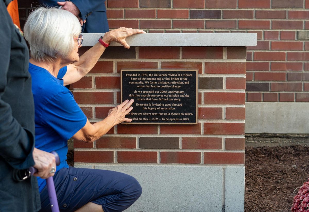 A volunteer reads the University YMCA’s time capsule plaque on Oct. 2, which includes the phrase “Our doors are always open—join us in shaping the future.” The YMCA installed the two time capsules last week, which are set to open in 2073.