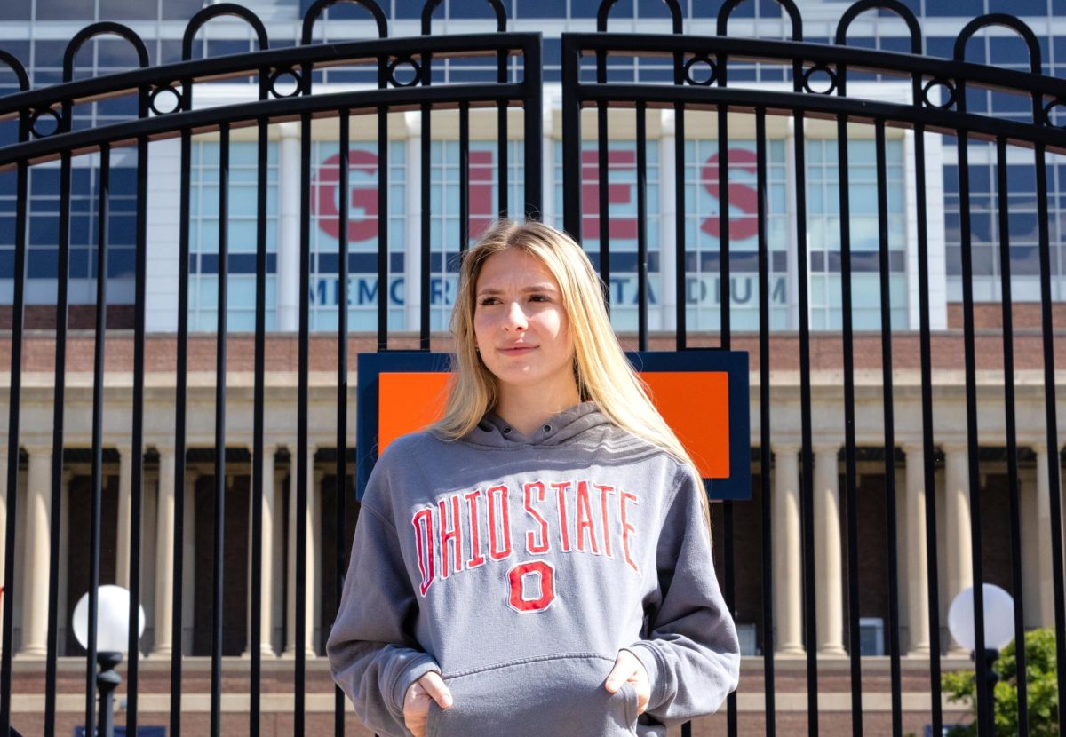 Rosa Maurello, senior in LAS, shows off her merchandise for Ohio State University in front of Gies Memorial Stadium. 