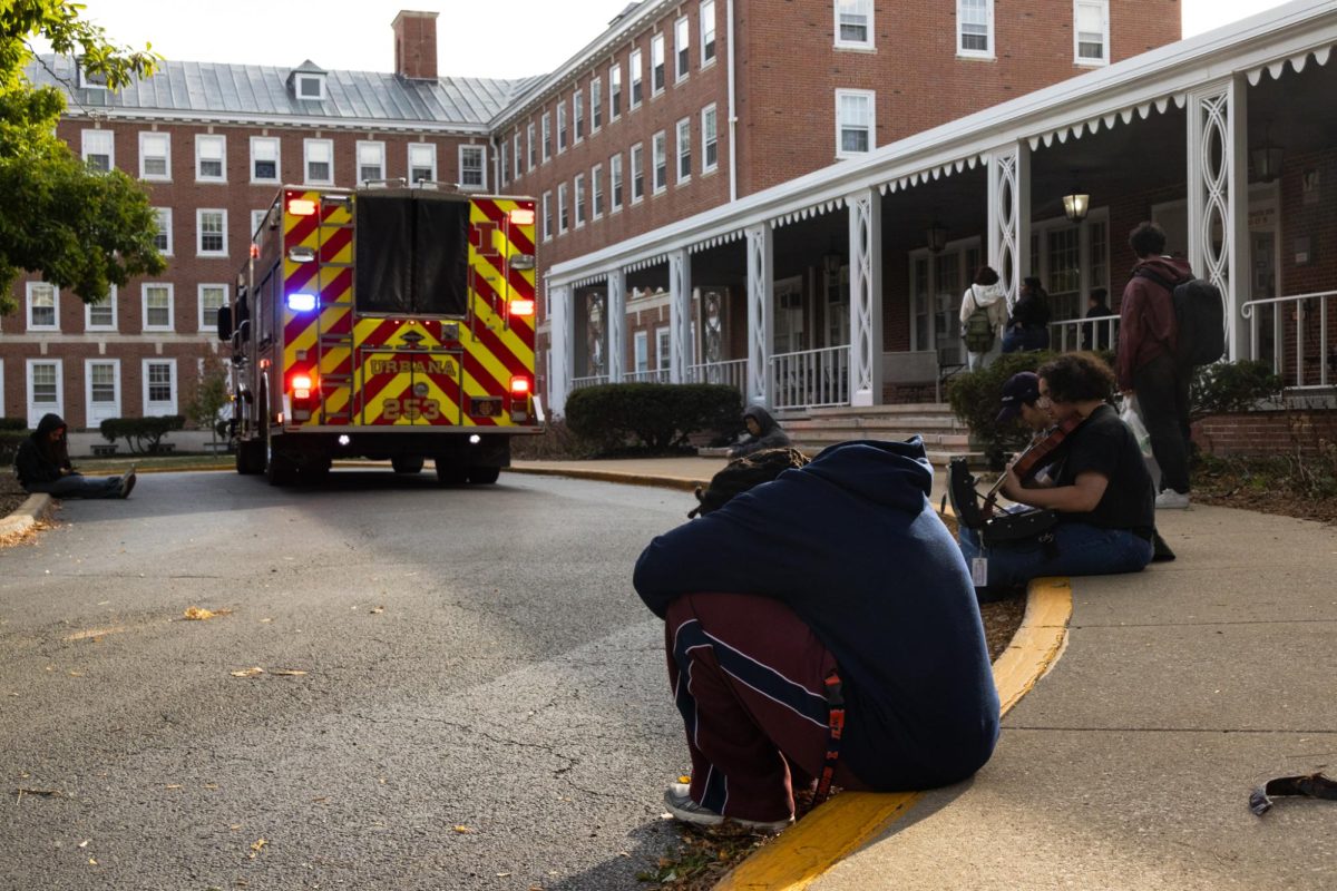 LAR residents sit on the sidewalk in front of LAR as Urbana firefighters respond to a fire inside on Friday. No injuries were reported in the fire. 