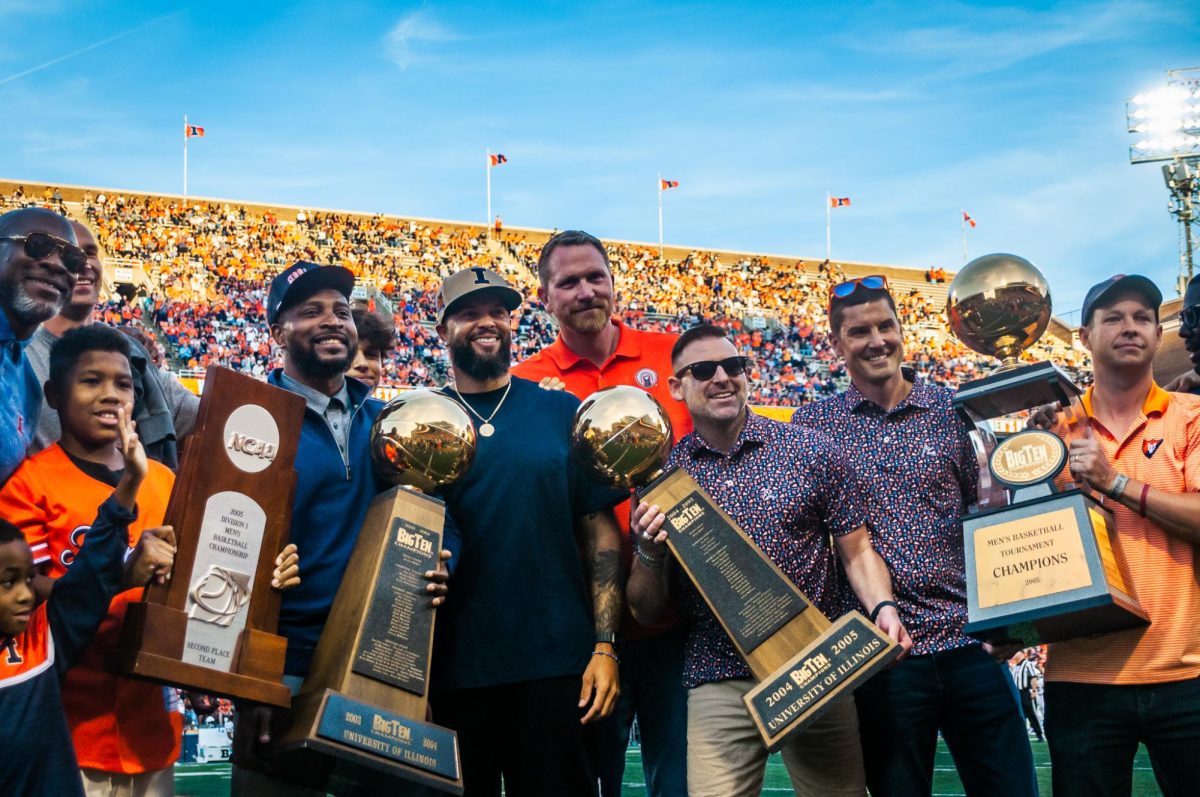 Members of the 2003-04 and 2004-05 men's basketball teams pose with team trophies on the field at Gies Memorial Stadium during a 20-year reunion on Aug. 29.