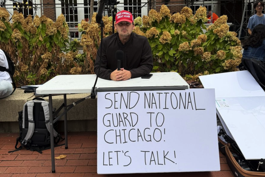 Cam Higby, a right-wing commentator, sits at a debate table on the Main Quad on Tuesday. Higby and Turning Point USA’s chapter at the University hosted the debate, which drew a crowd of onlookers and participants. 