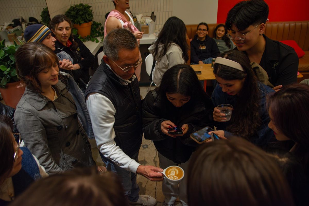 The crowd admires a latte at the fourth annual Latte Art Throwdown, held in BakeLab Pâtisserie and Café, located at 1807 S. Neil St. on Saturday. This year, 14 participants, many of them baristas from cafes across Champaign-Urbana, competed in a bracket-style tournament for prizes like coffee beans and brewing equipment.