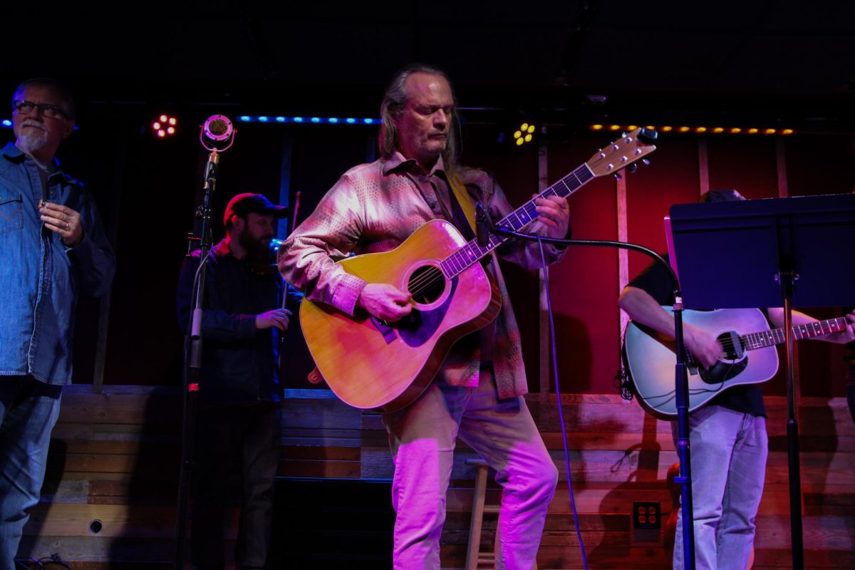 Performer Chris Johnson plays guitar in front of an audience at the Urbana Hootenanny held at the Rose Bowl Tavern in Urbana on Nov. 17. Many audience members joined the performers on stage with various instruments throughout the event.