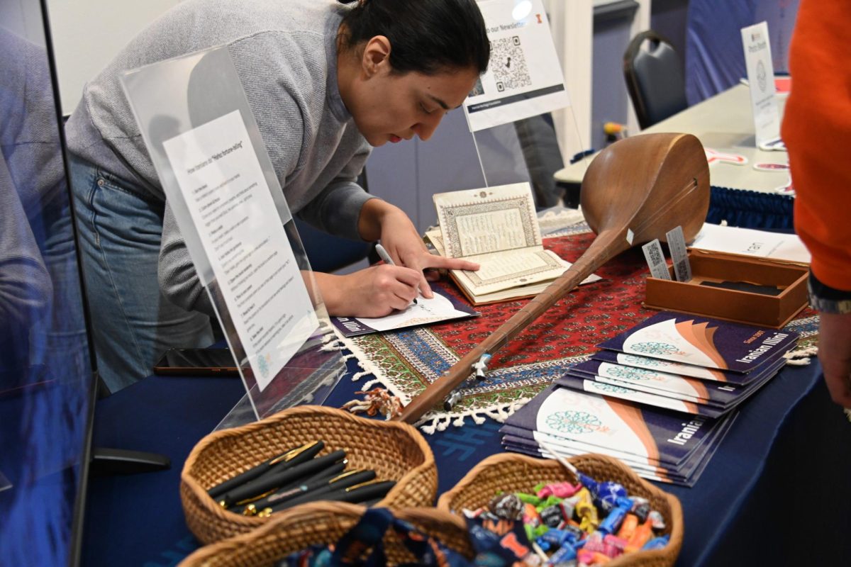 Members of the Champaign-Urbana community come together in the Illini Union to celebrate the diversities of the world on Nov. 18. The Iranian Culture table demonstrates writing in traditional scripture.