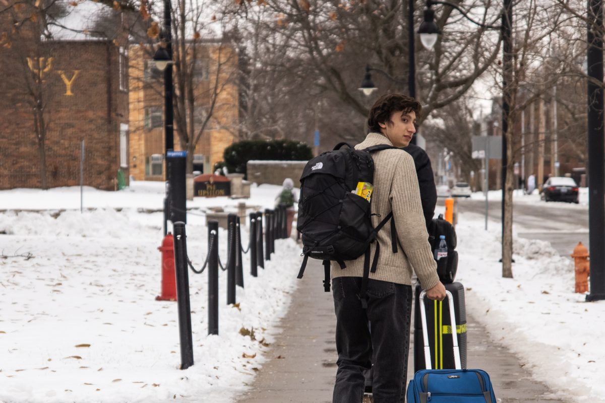 Students drag their luggage down snowy streets after returning to campus on Sunday. A Saturday winter storm left about 8 inches of snow on the ground in central Illinois, creating hazardous weather conditions.