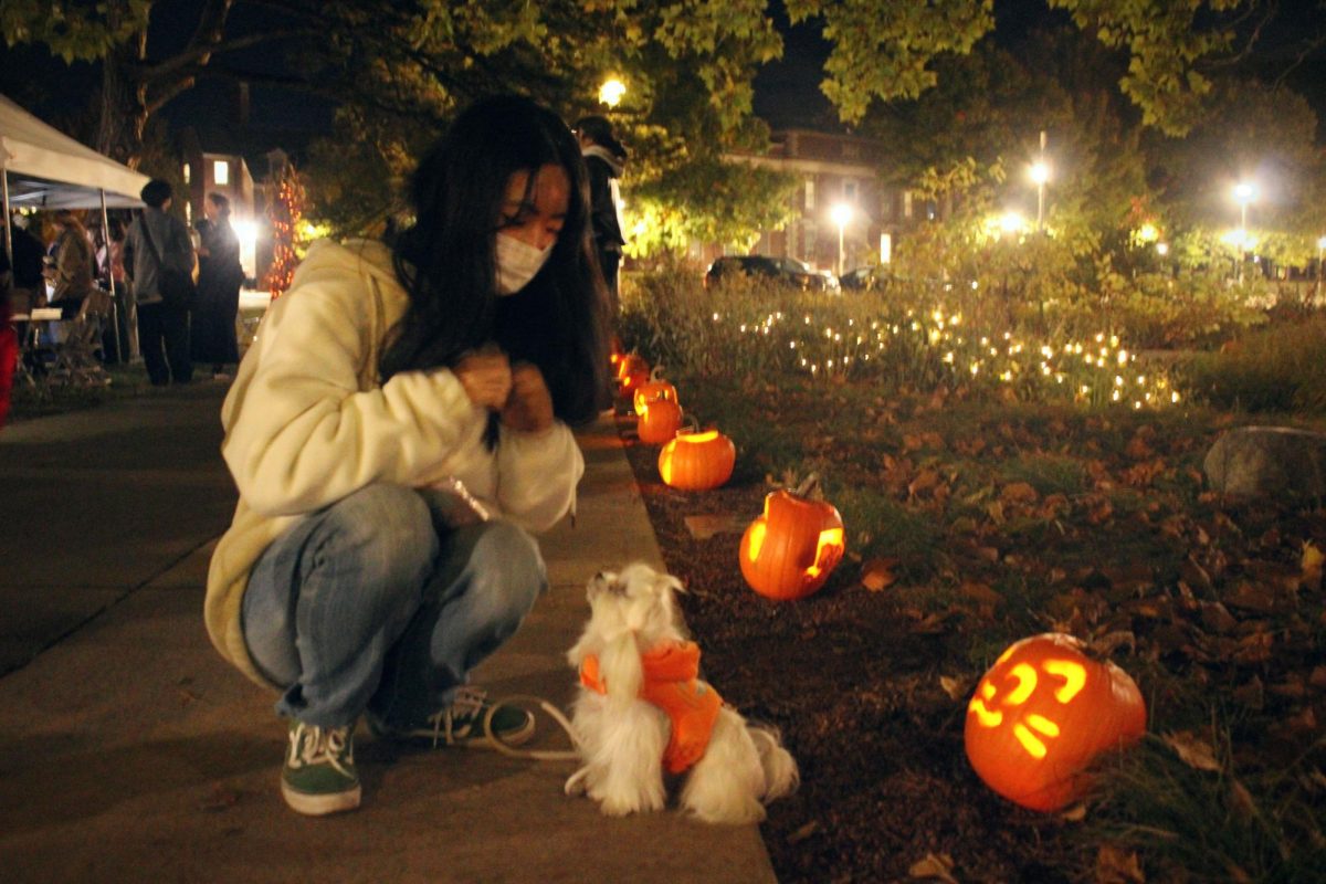 Yujin Choi, graduate student studying watershed ecosystems, plays with her dog at the Illuminating Art in Nature event in the Red Oak Rain Garden on Thursday.