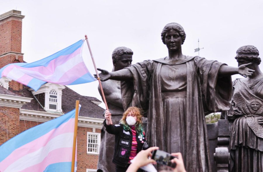 Rebecca Kimberly Goodman, senior in FAA, holds the transgender flag while standing beside the Alma Mater statue during the Trans Solidarity Rally on March 31, 2022. The rally was organized by CUTES and YDSA, and was held as celebration for Transgender Day of Visibility.