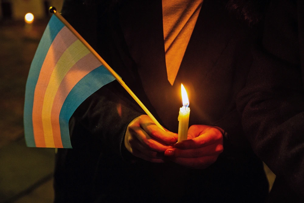 A demonstrator holds a candle and a transgender flag on Transgender Day of Remembrance in Bogotá, Colombia, on Nov. 20, 2020