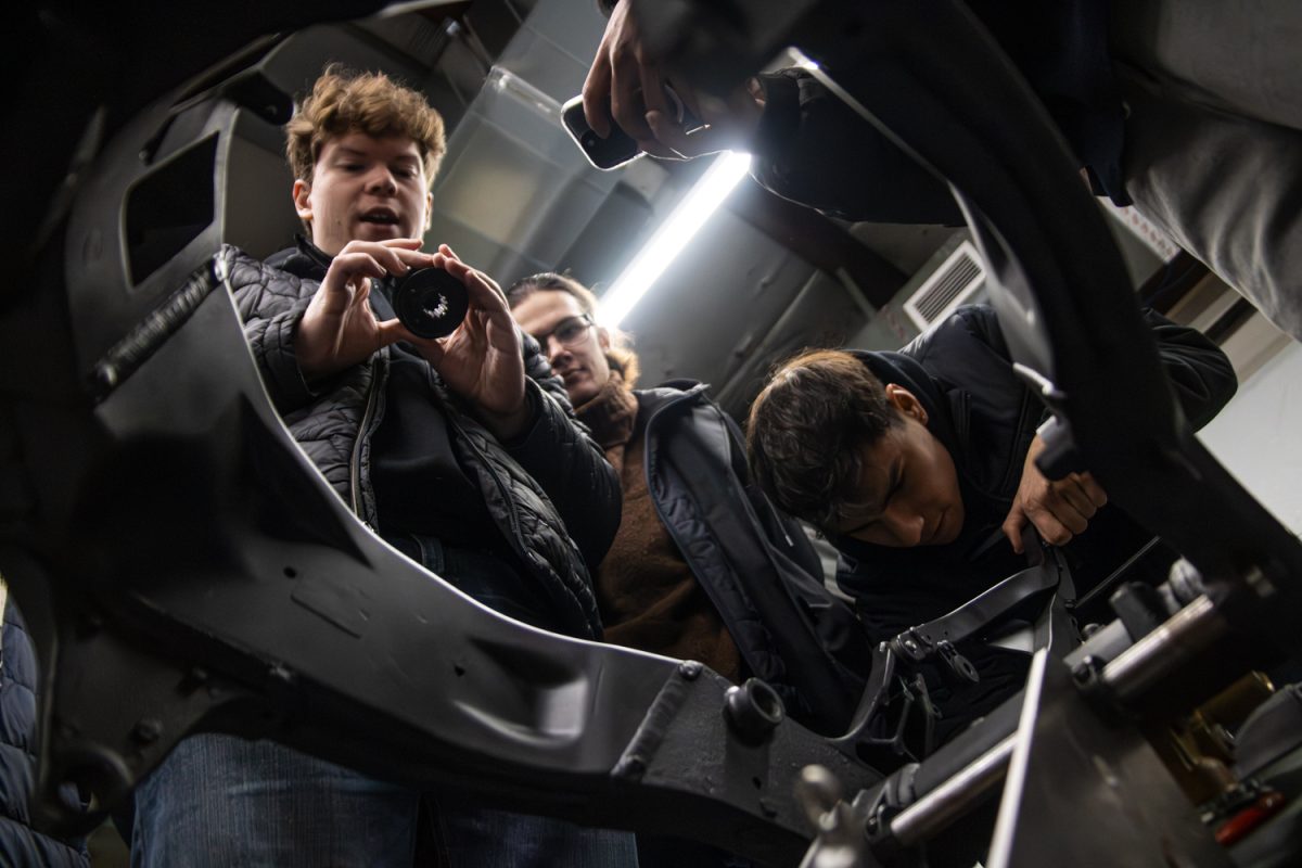 Members of Ghost Electric inspect different parts of the electric motorcycle they are currently building on Dec. 13. The students regularly meet at Right Balance Motors in Urbana to work on different parts of the bike.
