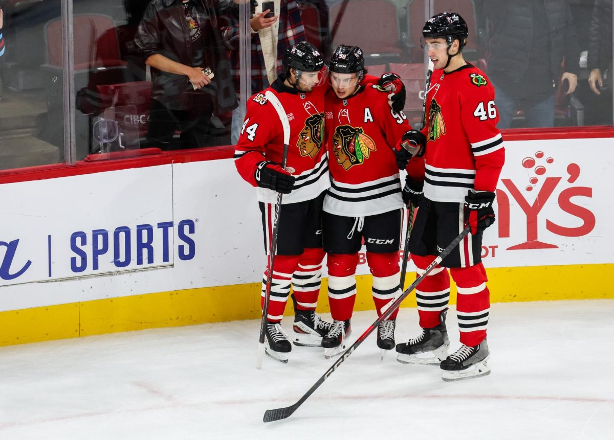 Blackhawks’ Louis Crevier and Wyatt Kaiser congratulate Connor Bedard (98) on his third goal that brought the Blackhawks up 5-2 during the third period against the Flames on Nov. 18, 2025, at the United Center. (Dominic Di Palermo/Chicago Tribune)