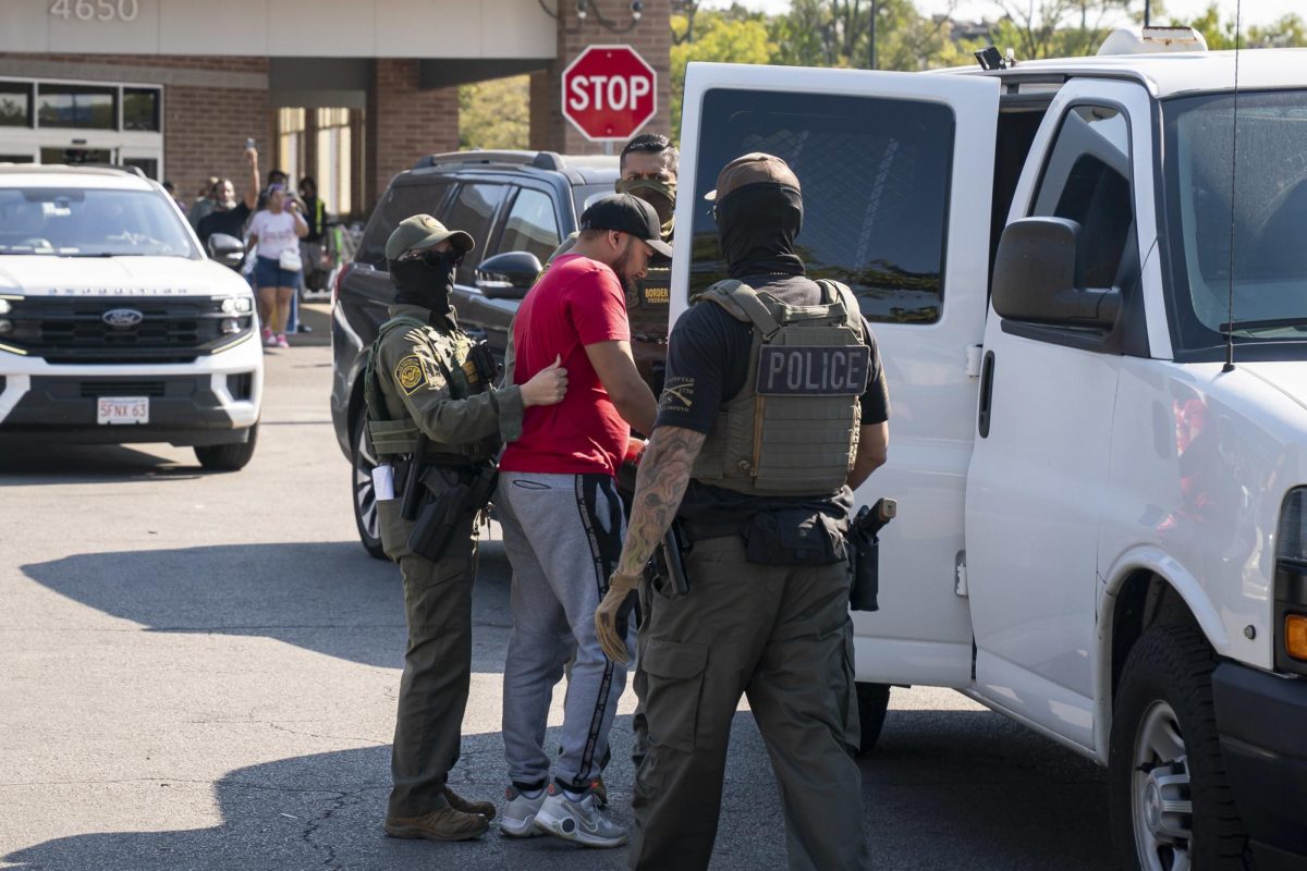 U.S. Immigration and Customs Enforcement officers place a detainee into a van during deportation operations in Chicago on Oct. 3. The Illinois Secretary of State’s office says it’s cracking down on federal agents swapping and altering license plates in the state.