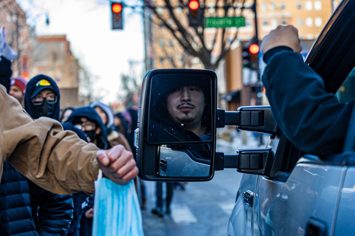 A man stopped in a truck on Green Street bumps fists with a protester as he waits for the crowd to pass on Jan. 30. The large crowd took up both lanes of the road, preventing most vehicles from getting through the protest.