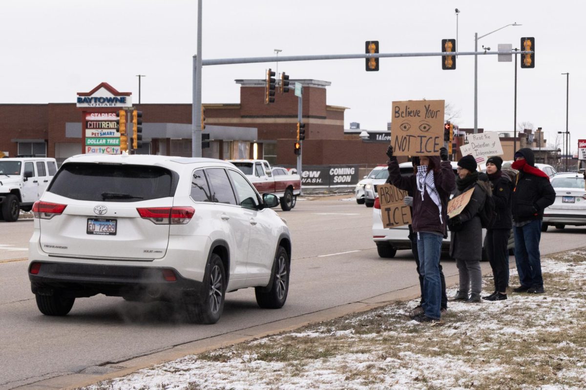 Protesters stand off of North Prospect Avenue in Champaign on Sunday, holding signs protesting against ICE following the killing of one woman in Minneapolis and shooting of two others in Portland this week.