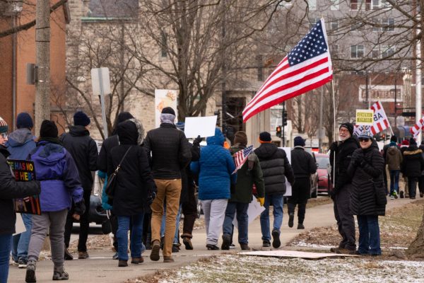 Anti-Trump protesters march around West Side Park in downtown Champaign on Sunday. The protest, organized by Champaign-Urbana Resistance Effort, was one of many against the Trump administration this month in the C-U area.