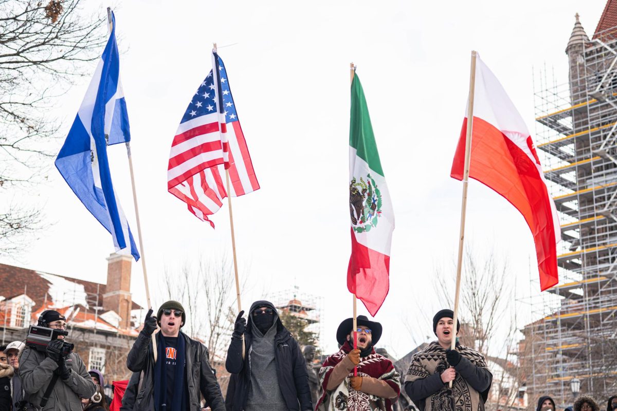 A group of protesters, including Joaquin Valencia, junior in Engineering (middle-right) hold their flags high as they stand in front of the Alma Mater during the walk out against ICE on Jan. 30. The anti-ICE protest follows federal agents killing Alex Pretti and Renee Good, two U.S. citizens in Minneapolis.