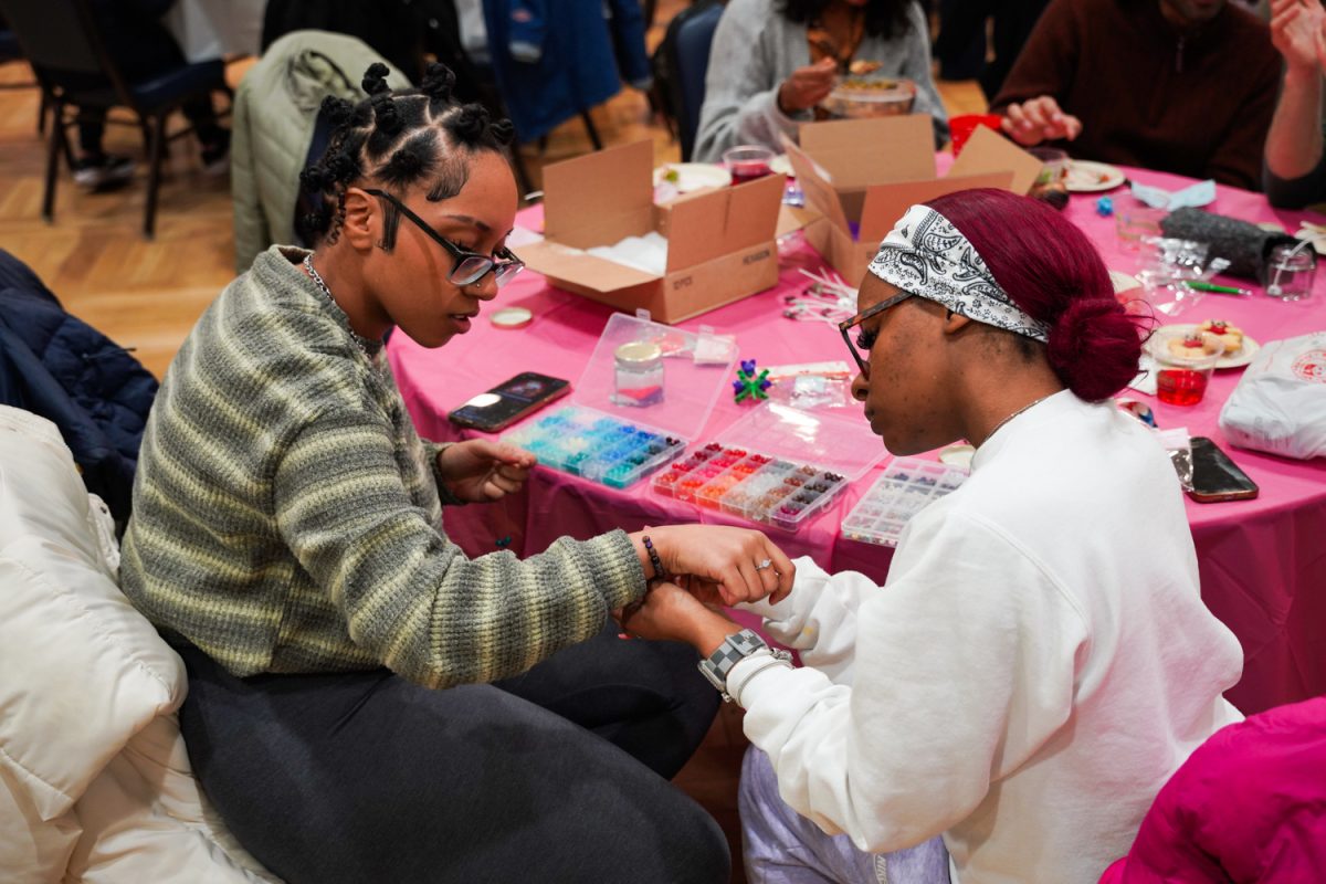 Two students try on handmade bracelets during the Illinite Me, Illinite Me Not event at the Illini Union on Friday. Students participated in interactive craft activities throughout the evening.