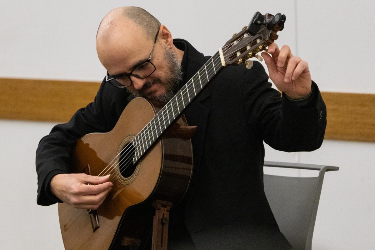 Dr. Guido Sánchez-Portuguez, assistant professor in FAA, tunes his acoustic guitar during his concert performance at the Champaign Public Library on Jan. 30.